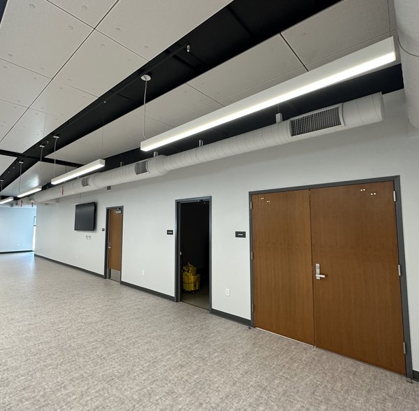 Exposed white spiral supply duct with linear grilles in a corridor